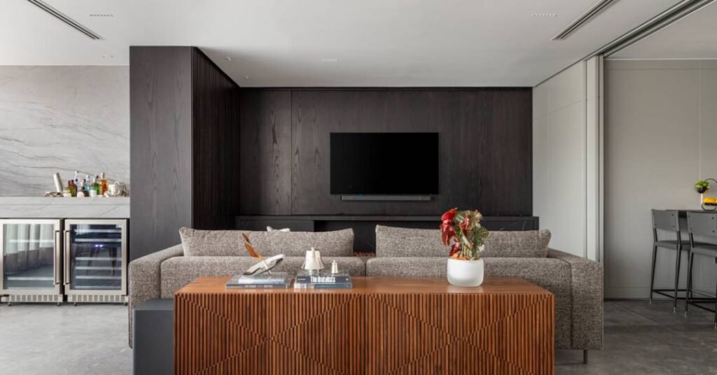 Elegância sóbria: tons de cinza e painéis de madeira ebanizada marcam apê
