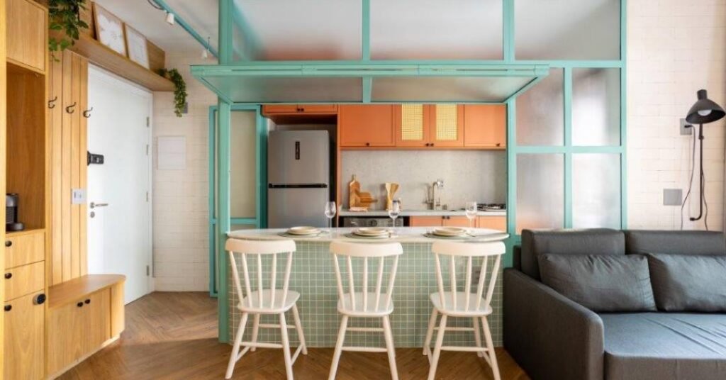 Divisória azul com vidro abriga balcão e divide cozinha e sala neste apê de 42 m²