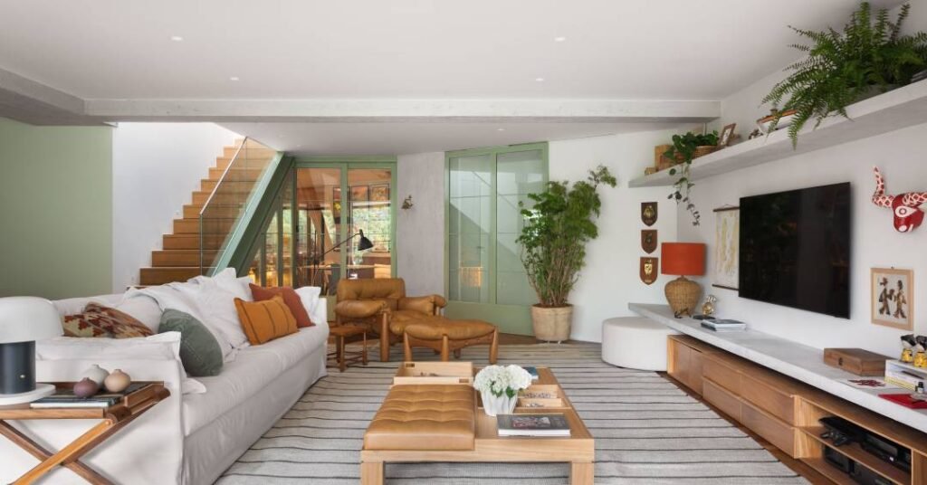 Cobertura tem jardim elevado no terraço e marcenaria verde elegante entre cozinha e sala