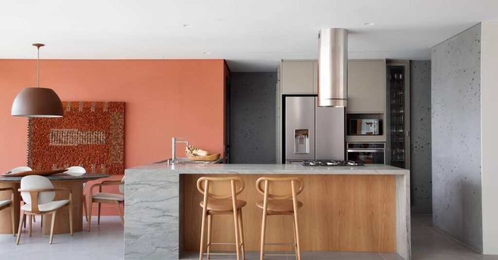 Apartamento tem laminado melamínico em tom fendi na cozinha e parede terracota na sala
