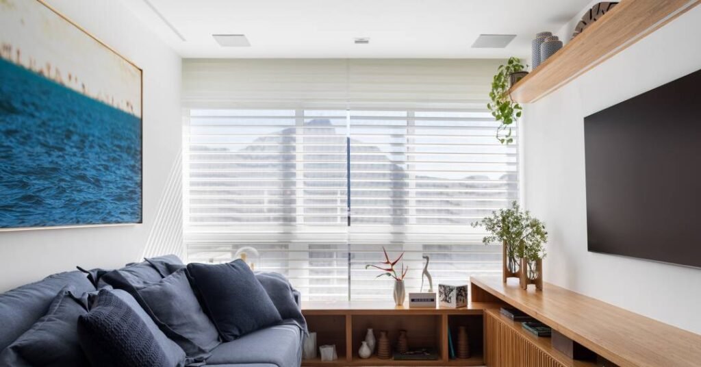 Apartamento tem banco ao longo da janela da sala e porcelanato listrado no banheiro