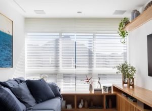 Apartamento tem banco ao longo da janela da sala e porcelanato listrado no banheiro