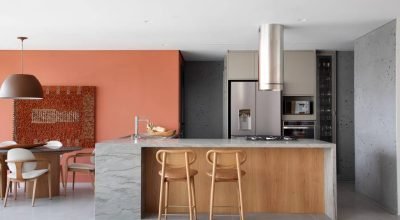 Apartamento tem laminado melamínico em tom fendi na cozinha e parede terracota na sala