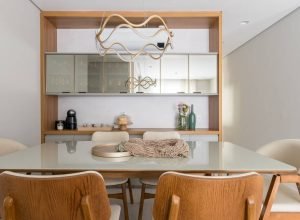 Marcenaria na sala de jantar de apê abriga buffet, armários aéreos e cristaleira com vidro reflecta