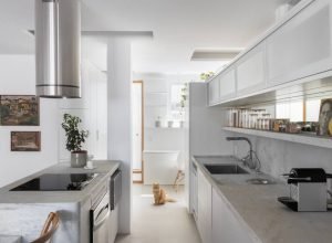 Neste apartamento de 97 m² a ilha de pedra se estende até se converter em mesa de jantar